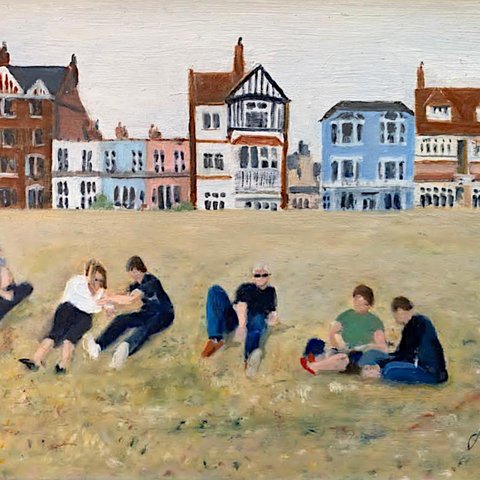 People sitting around relaxing on a sunny day in the open air, with houses in the distant background.