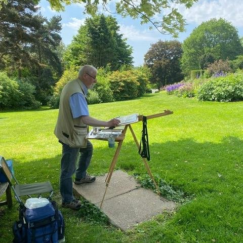 Artist standing behind easel painting the surrounding gardens.
